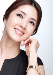 蘆久保慶那女士穿著黑色短袖女襯衫，她左手戴著金手鐲，她是日籍成熟美女時尚模特兒，她的身高是170厘米，身材十分苗條俏麗。