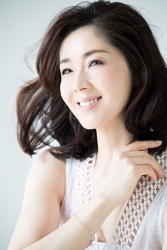蘆久保慶那女士穿著白色短袖女襯衫，右手戴手鐲，她是日籍成熟美女時裝模特兒，她的身高是170厘米，身材十分苗條俏麗。