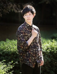 大偉亞穿著一件『（花卉圖案）黑色剪裁襯衫・黑色褲子』，他站著，他是日本英俊帥氣『時裝男模特兒･男演員』。