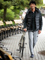 博顕穿著『深綠色外套・牛仔褲』，旁邊有一輛自行車，正在走路，他是日籍英俊帥氣『男演員･時裝男模特兒』。