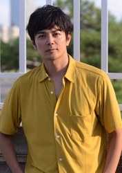 伸一郎穿著黃色剪裁襯衫，他站著，他是日本成熟男模特兒。