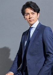 伸一郎穿著藍色西裝，他站著，他是日本成熟男模特兒。