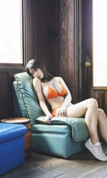 菊沖姬羅小姐是『日本・亞洲』的『凹版偶像・寫真偶像・泳裝偶像｜泳裝模特兒・泳衣女模・海報女郎｜女演員』，她身穿橙色比基尼泳衣，坐在綠色沙發上。